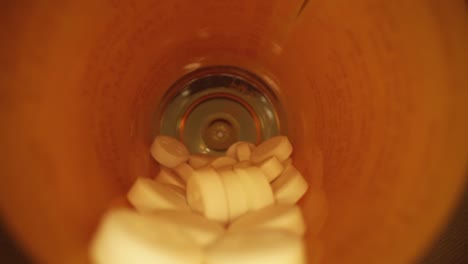 pulling-out-of-the-entire-length-of-a-orange-prescription-pill-bottle,-revealing-empty-blue-bottle-cap