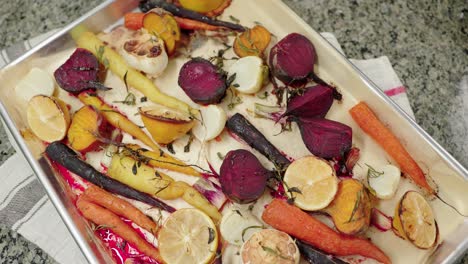 a colorful tray of roasted root vegetables with herbs and lemon for a rustic meal