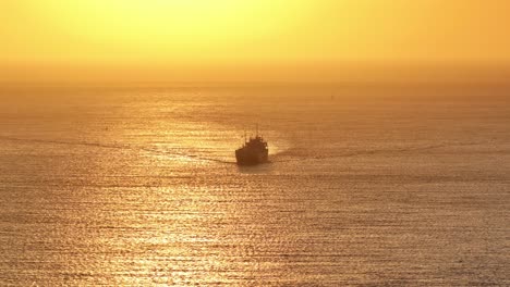 zoomed drone panning shot of a cargo vessel sailing over the north sea during sunset