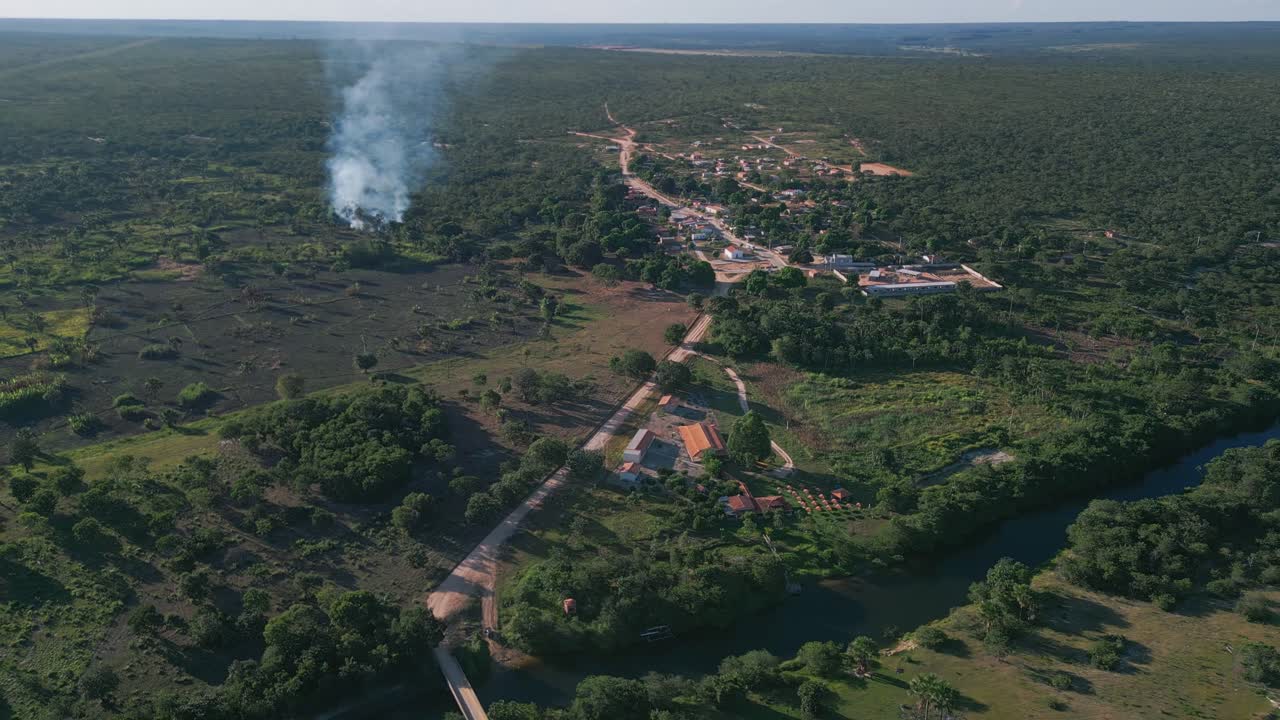 Rappresentazioni aeree ad alta quota mostrano insediamenti lineari lungo una strada sterrata all'incrocio di un fiume, con protezione della foresta a galleria ripariale, savana di Cerrado circostante, attività di gestione degli incendi visibile