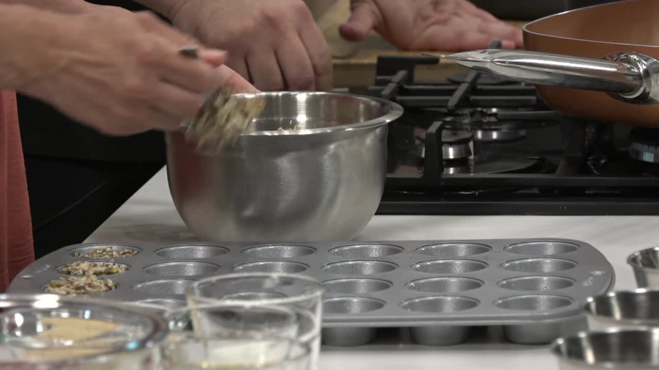 The assistant cook fills a steel baking pan with the honey-cereal mixture, divides scale the dough into portions with a spoon and fills the baking pan.