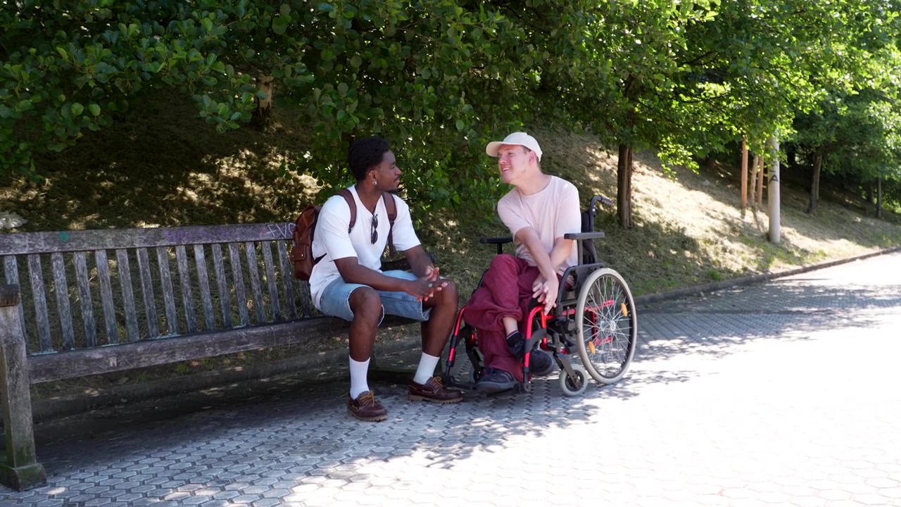 Due giovani che parlano seduti su una panchina del parco