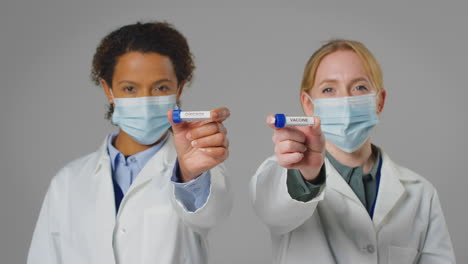 fotografía de estudio de trabajadores de investigación de laboratorio con máscaras faciales sosteniendo tubos de ensayo etiquetados con omicron y vacuna