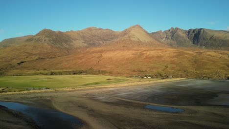 flying over gravel beach towards red cuillin mountains at sunset at glenbrittle isle of skye scotland