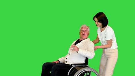 young woman finally taking her disabled father in a wheelchair home on a green screen, chroma key