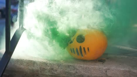 cámara lenta de humo verde que sale de una máscara de asesino en serie jack-o-lantern en un porche