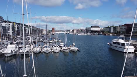 Flying-over-huge-anchor-statue-and-over-sailing-boat-masts-to-reveal-Solheimsviken-with-puddefjord-bridges-and-Bergen-city-during-sunny-day---Norway-aerial-view