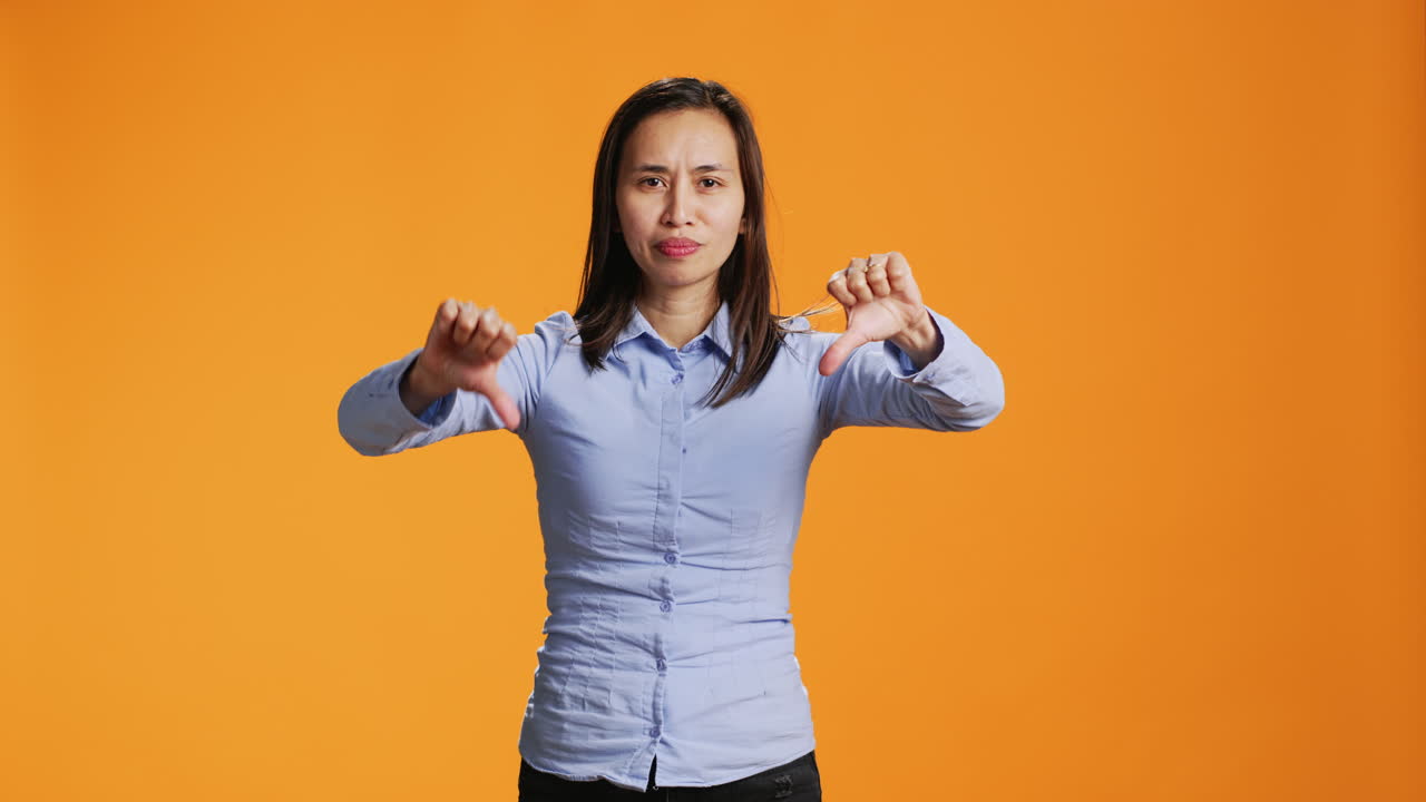 스튜디오 카메라 앞에서 엄지손가락을 내려주는 아시아인