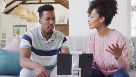 una feliz pareja afroamericana usando una tableta juntos en la sala de estar.
