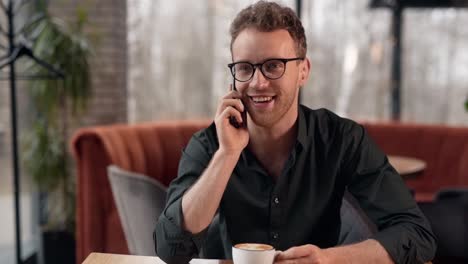 apuesto joven hablando por teléfono en una cafetería o café