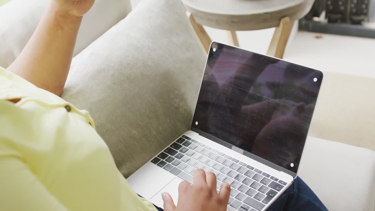 video de una mujer afroamericana de tamaño grande sentada en el sofá con una computadora portátil con espacio para copiar
