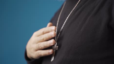 catholic and orthodox christian man making the sign of the cross and kissing the necklace of the cross.