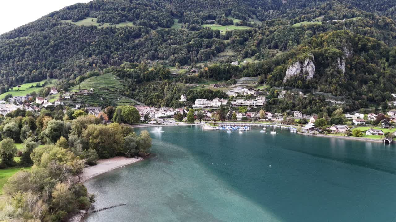 Walensee lake beautiful aerial drone view surrounded by Swiss alps, green hills and villages of Wessen, Amden and Quinten, drone pushes towards