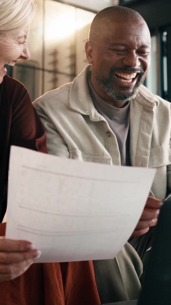Diverse Colleagues Laughing While Reviewing Documents in Office