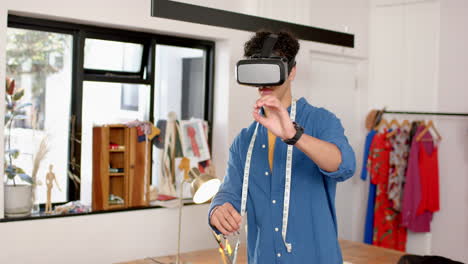 biracial male fashion designer using virtual reality headset in studio, slow motion