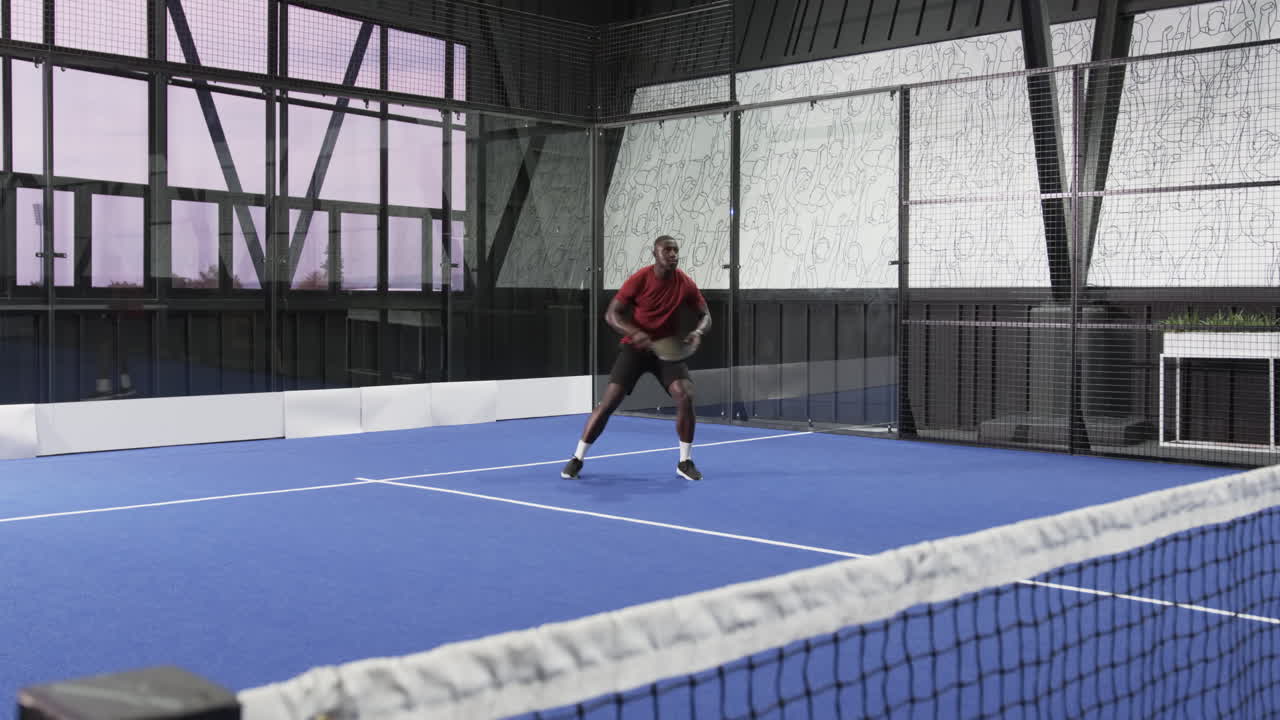 Man playing padel tennis on indoor court, holding racket and moving energetically
