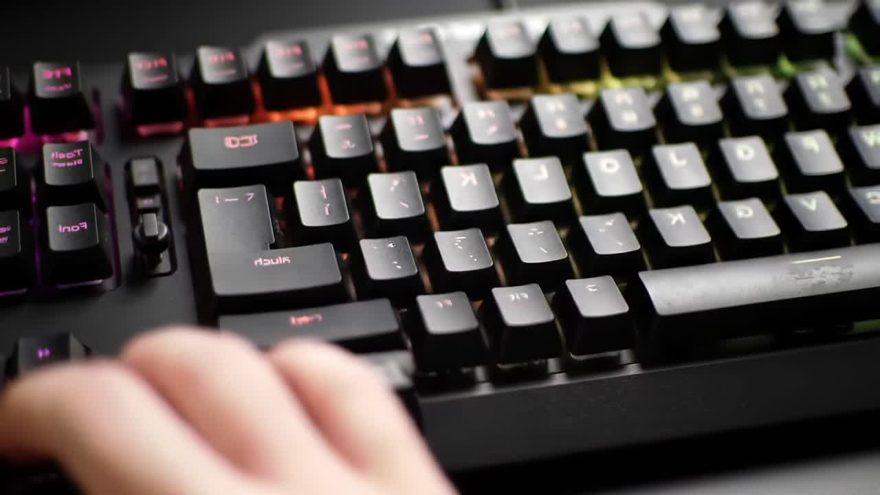 A Close-Up View of a Human Hand Interacting with a Colorful Backlit Keyboard, Showcasing Modern Gaming Technology and Ergonomic Design Features