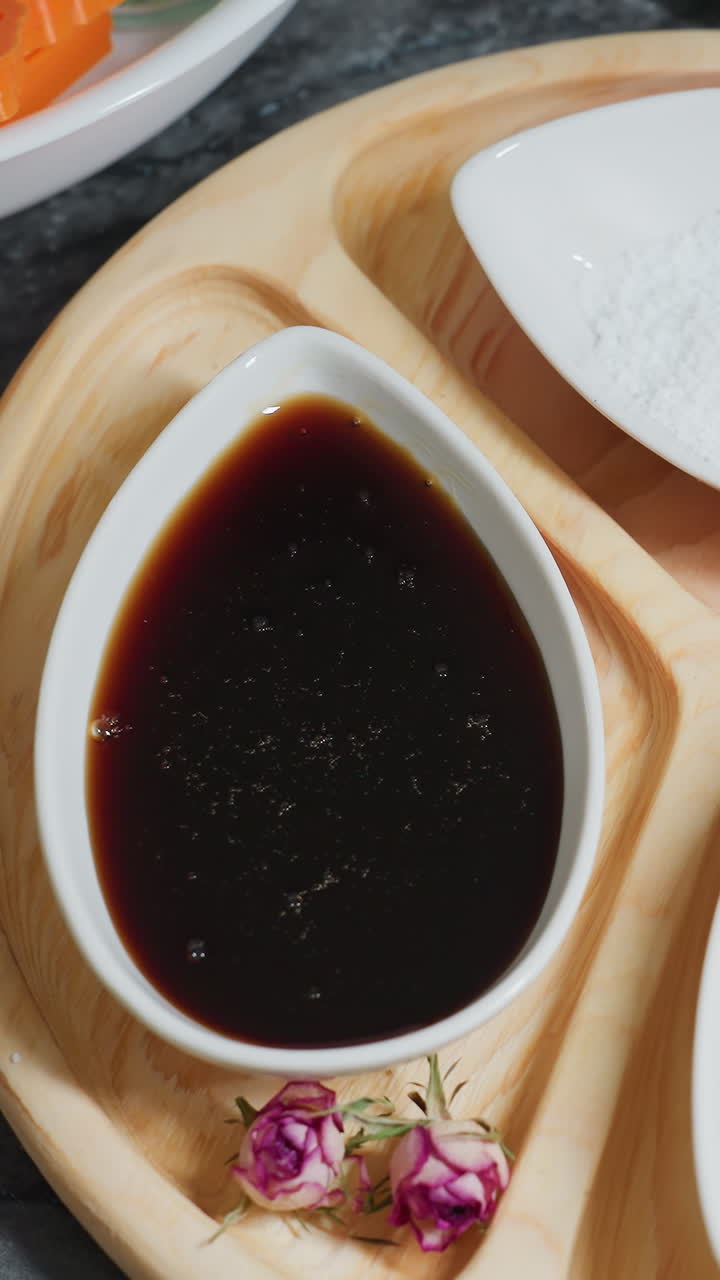 세라 그에 있는 의 클로즈업, 나무판에 있는 설탕 가루와 은 향신료, 작은 분홍색 꽃이 장식적인 손짓을 덧붙이고, 베이킹 재료와 쿠키 커터가 배경에 배열되어 있습니다.