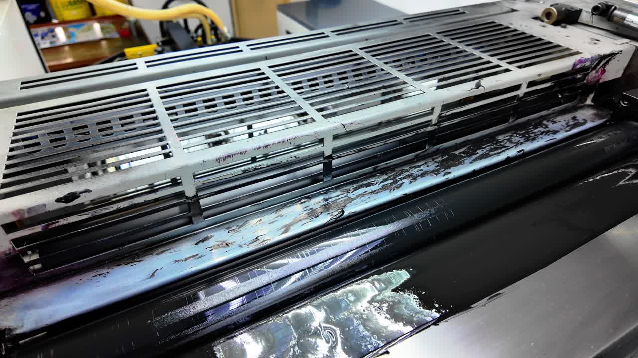 Close examination of the lithographic printing process showcasing the application of printing ink on the press. The machinery operates efficiently, vital for quality print production.
