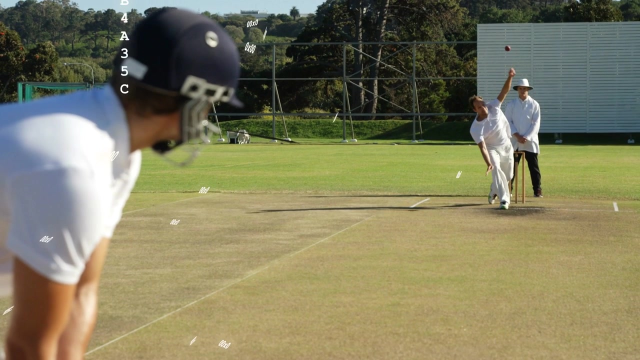 Hjelmklædt batsman krumbøjet, ser bowleren løbe og kaste cricketbolden for at forsvare gærdet.