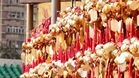 close-up view of red and gold wishing ribbons hanging in a vibrant display against an urban backdrop.