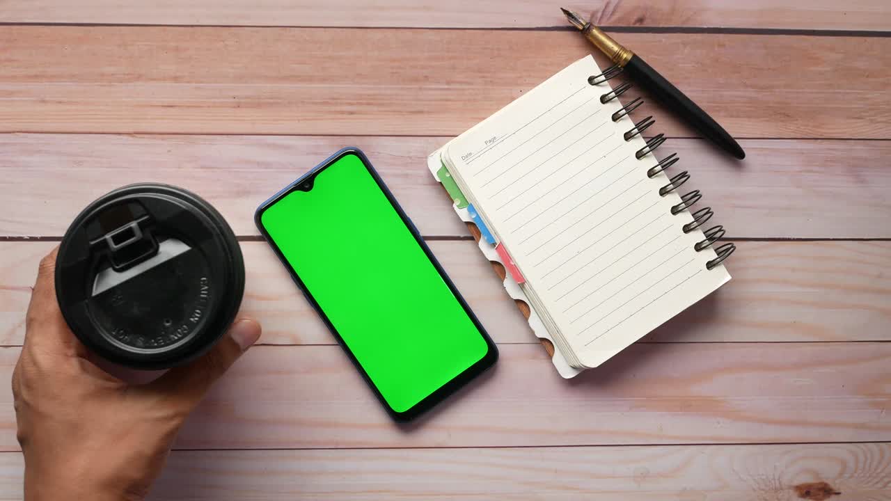 top view of man putting smart phone and coffee cup on table