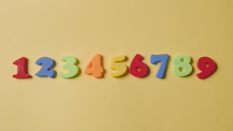 Studio-Overhead-Shot-Of-Plastic-Numbers-Arranged-In-Order-On-Yellow-Background-