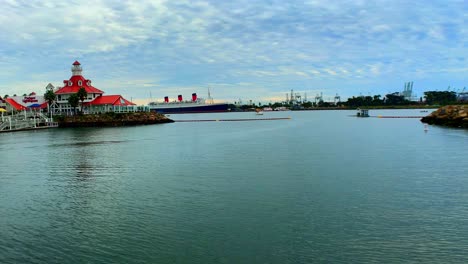 Panning-right-shot-of-the-light-house-and-the-harbor-of-Shoreline-Village-in-Long-Beach-Ca-with-a-boat-crossing-by