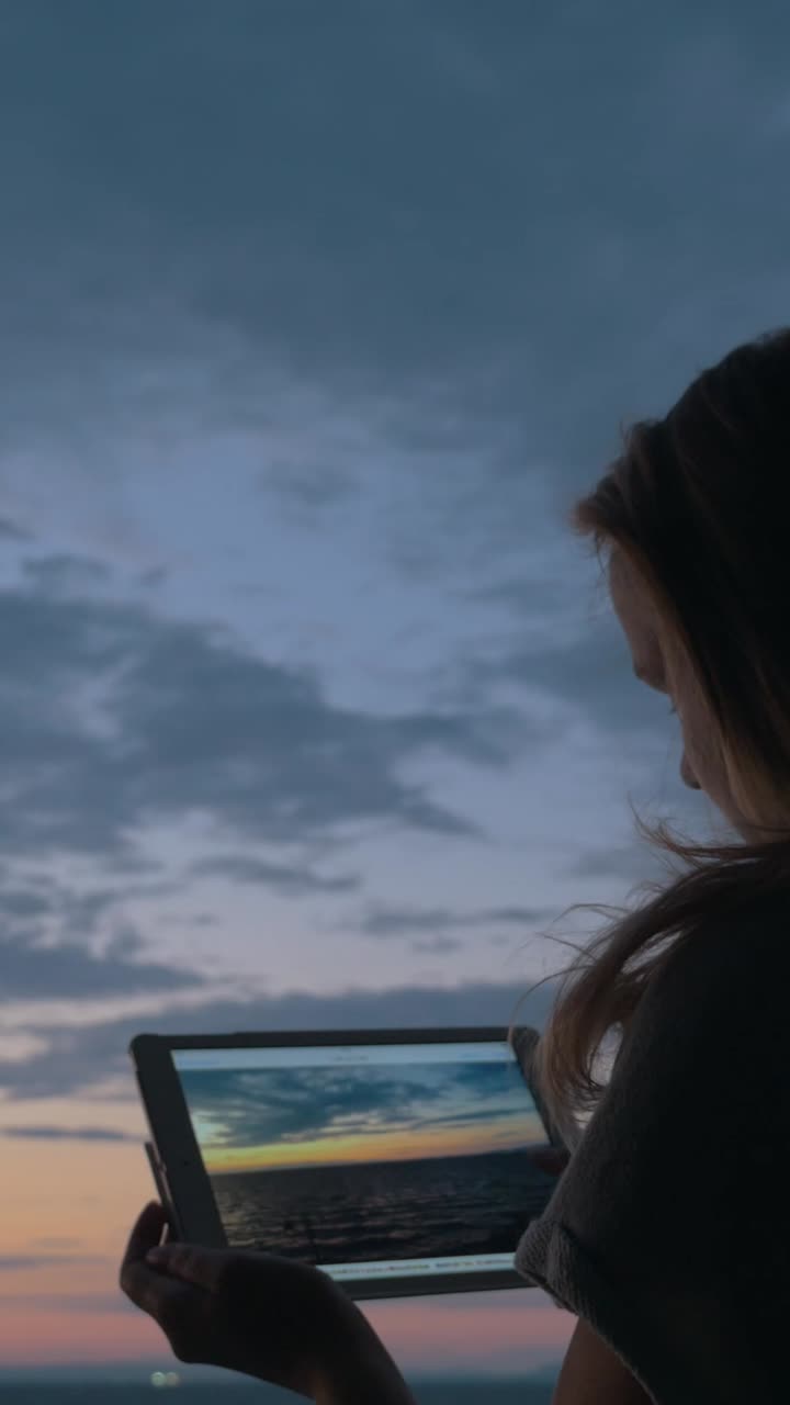 Tablet ile gün batımının fotoğrafını çeken kadın