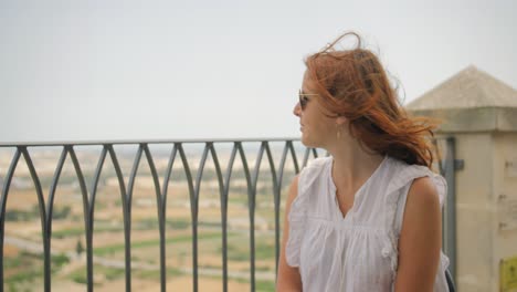 female tourist in sunglasses sitting outdoor with hair blown by the wind