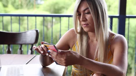 young woman working on laptop on outdoor restaurant terrace