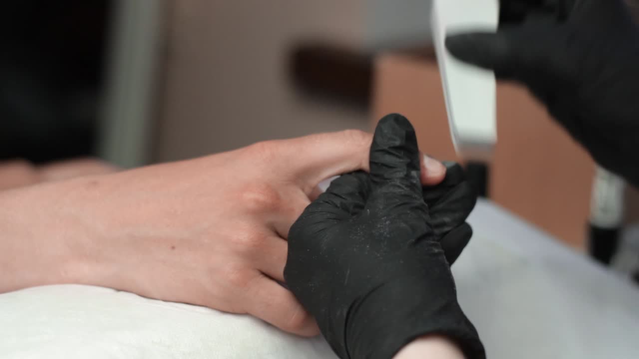 Side on view of a manicurist buffing the nails of a client