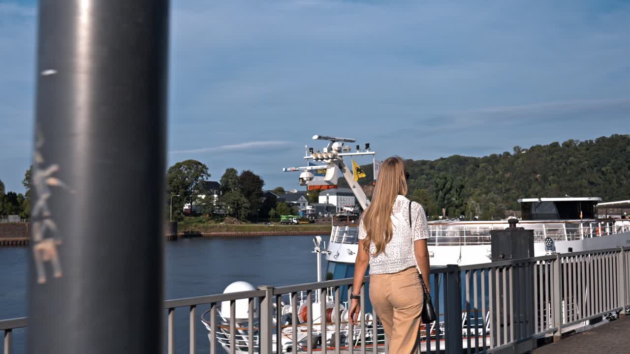 Blonde woman wading in the waters of the Moselle river in Koblenz with the historic German city's riverfront in the background