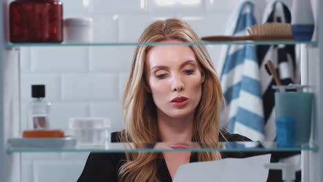 View-Through-Bathroom-Cabinet-Of-Young-Businesswoman-Practising-Speech-Before-Going-To-Work