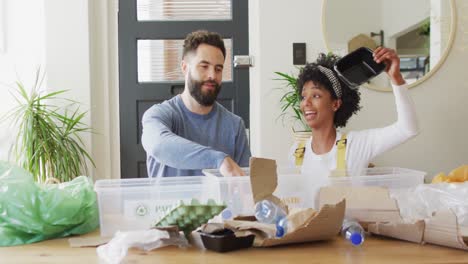 video de una pareja feliz y diversa divirtiéndose clasificando el reciclaje en casa