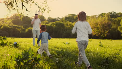 joven padre con su pequeño hijo jugando al fútbol en el campo de fútbol
