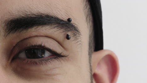 close-up-of-hispanic-man-eye-looking-at-camera-wearing-eyebrow-piercing-on-white-background-reflection-vision-eyesight