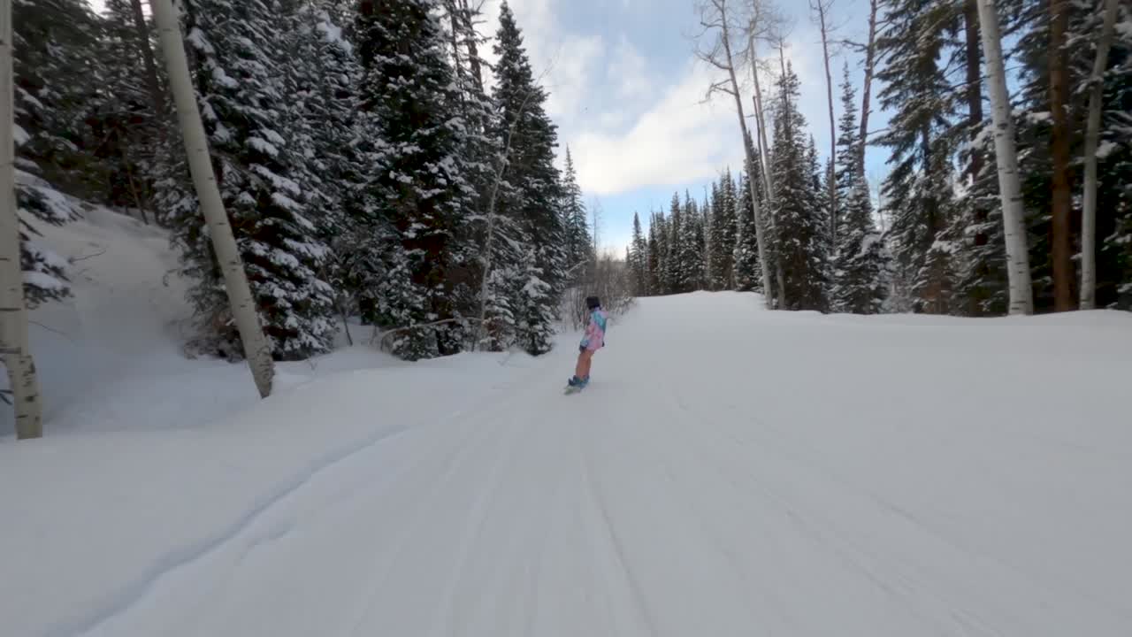 следите за женщиной-сноубордисткой, быстро спускающейся по горнолыжному склону