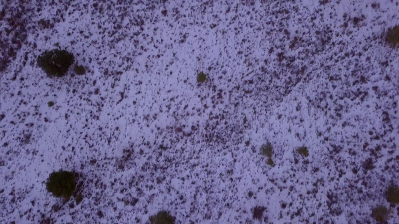 drone volando sobre campos nevados con un pueblo de montaña al atardecer con nieve y hielo en el campo