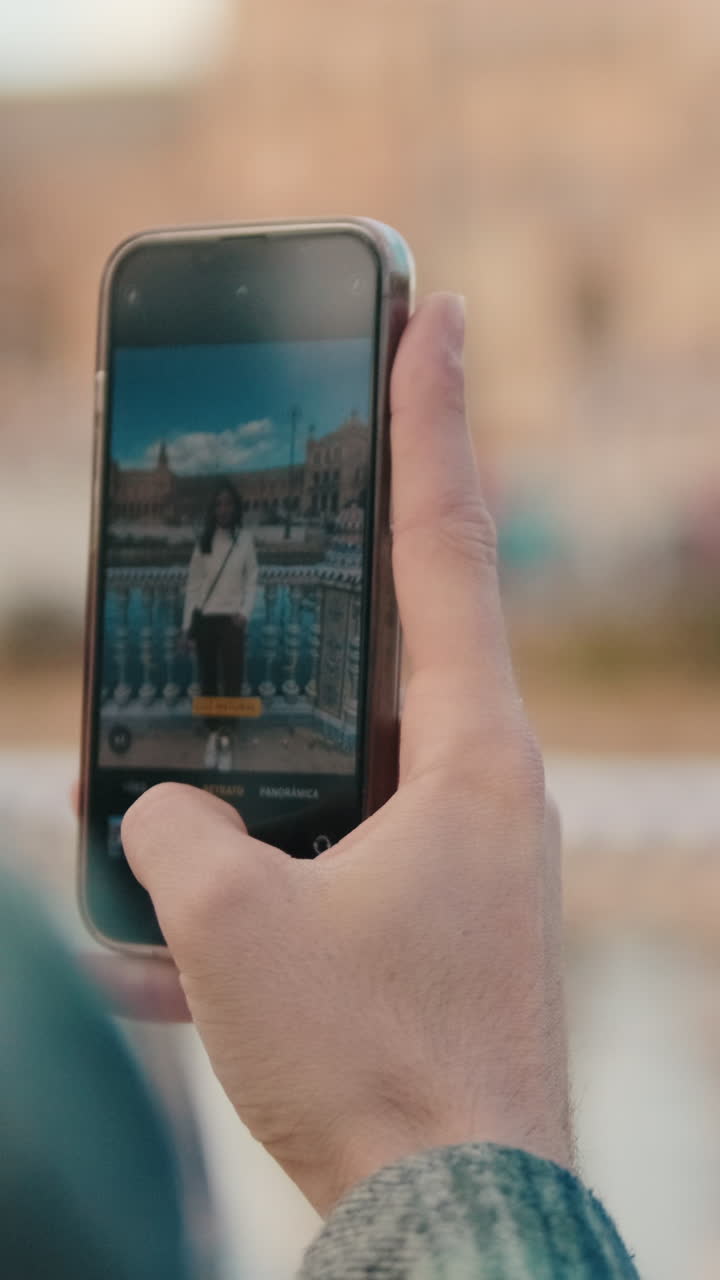 Close up of man's hand holding mobile phone, taking photo of girlfriend