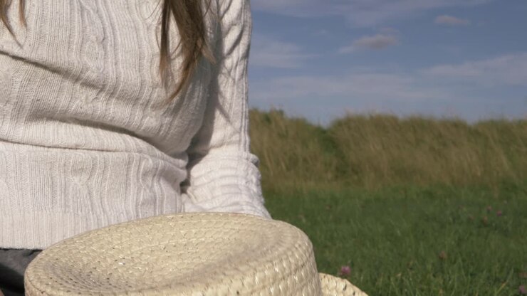 Donna che indossa un cappello di paglia in un campo, foto ravvicinata