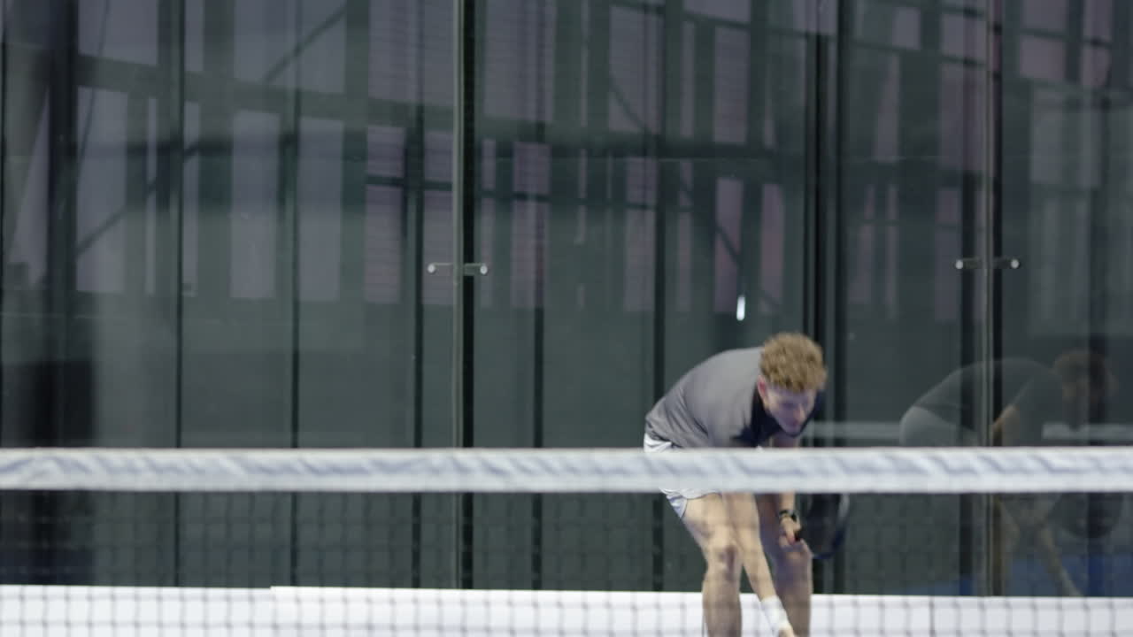 Young man playing padel tennis, focused and ready at indoor court