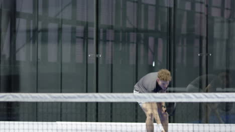 young man playing padel tennis, focused and ready at indoor court