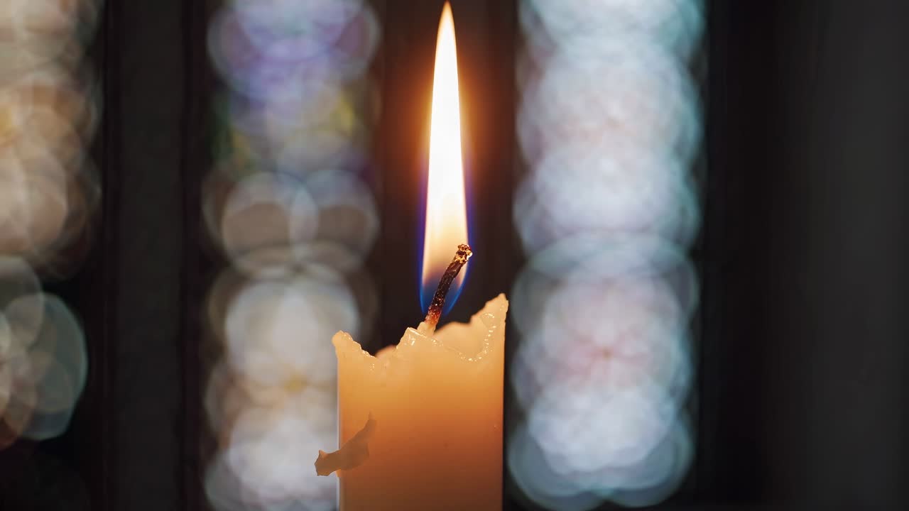 Fladdrande ljuslåga som brinner i mörkret med bokeh-bakgrund