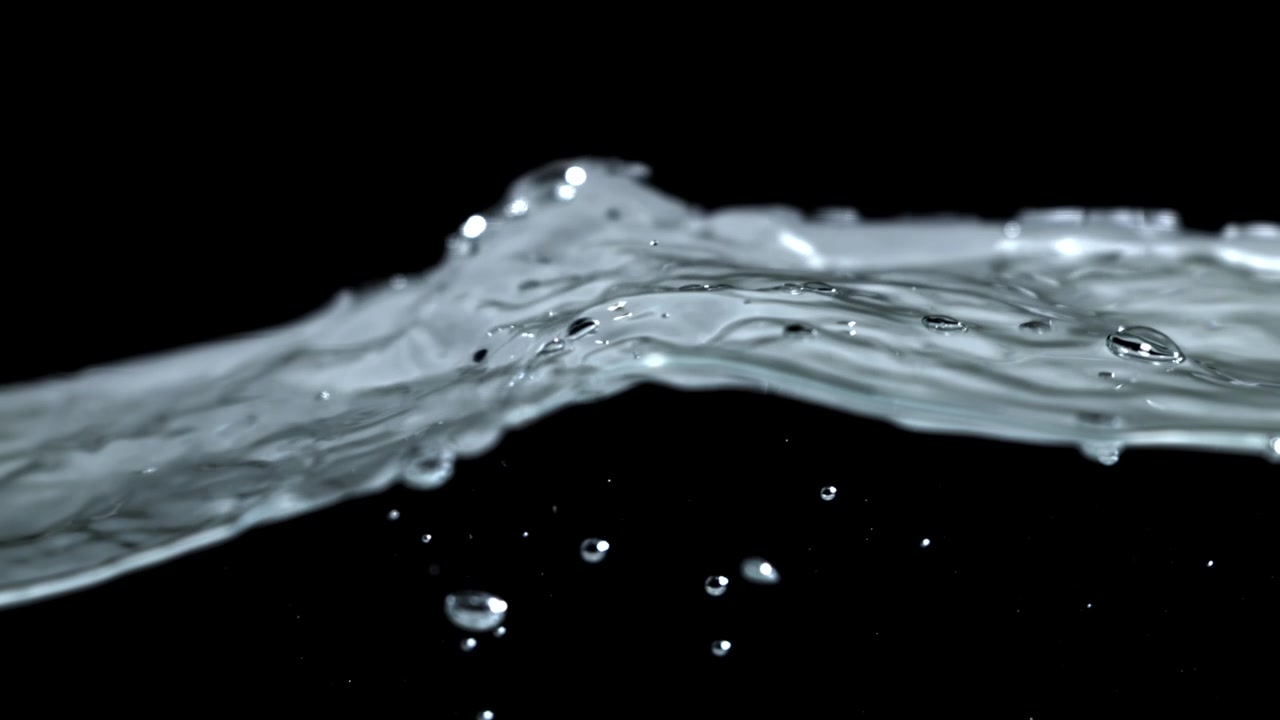 Close-up of Clear Water Flowing with Droplets on Black Background