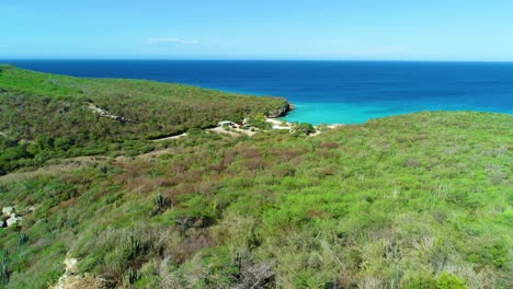 Drone-push-in-above-exposed-rocky-ridgeline-reveals-secluded-tropical-sandy-beach-cove