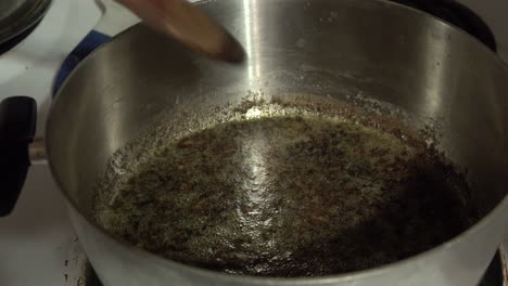 Boiling-pot-of-bubbling-green-brown-liquid-sludge-on-stove-top-in-kitchen