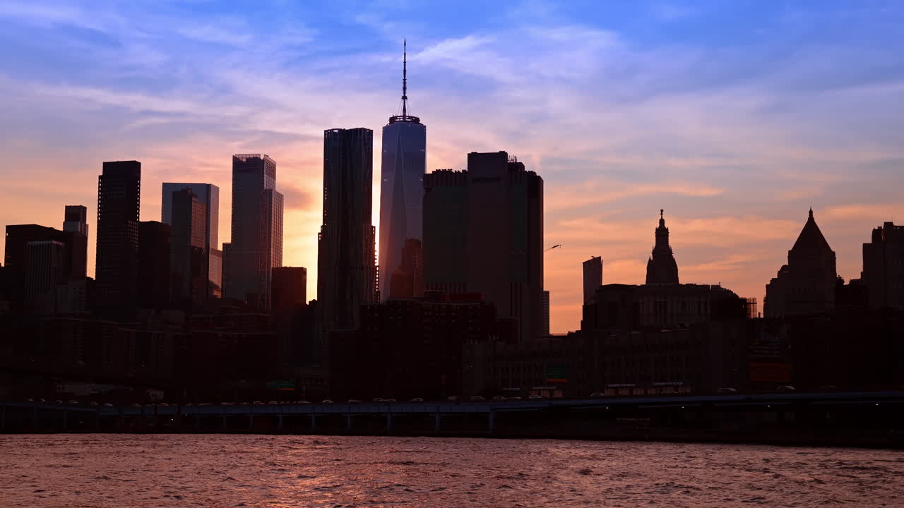 Nueva York, EE. UU., 25 de diciembre de 2025: Los rascacielos del Bajo Manhattan se perfilan bajo un vibrante cielo al atardecer. Siluetas oscuras del One World Trade Center y de los edificios del Distrito Financiero.