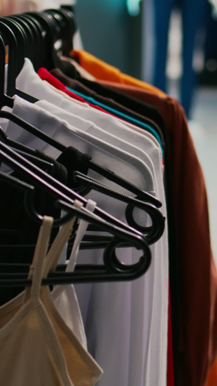 Vertical video: Multiple formal or casual clothes hanging in clothing store