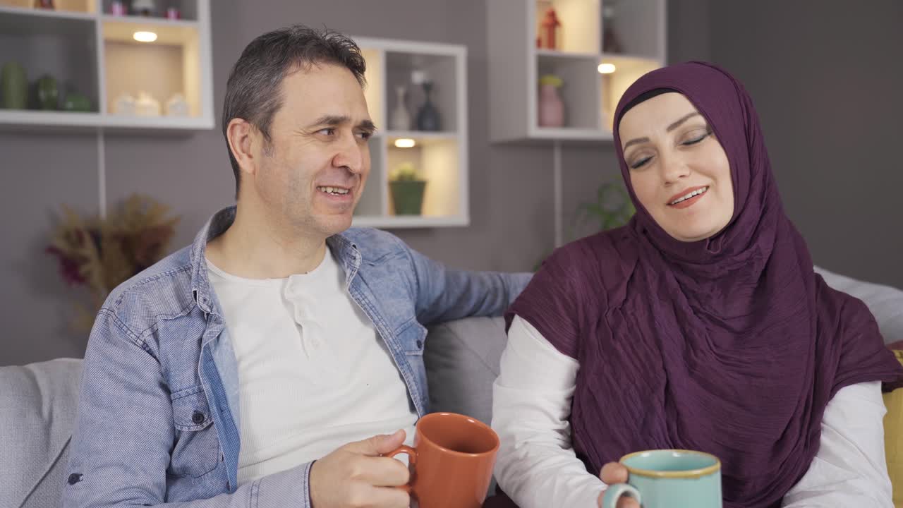 Premium stock video - Happy muslim woman in hijab and her husband at home.